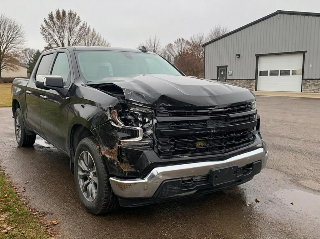 Pickup truck with classic Wisconsin deer strike damage to front grille, hood, and headlights.