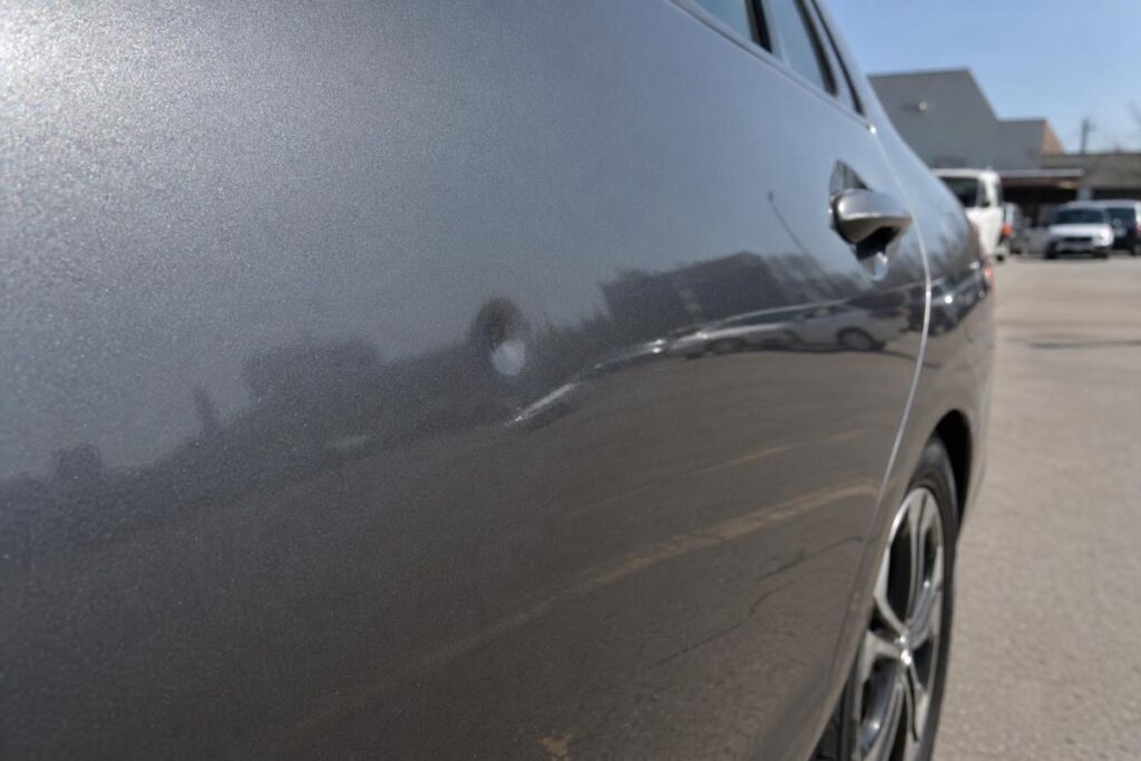 Close-up of a typical parking lot door ding on a vehicle door panel before paintless dent repair.