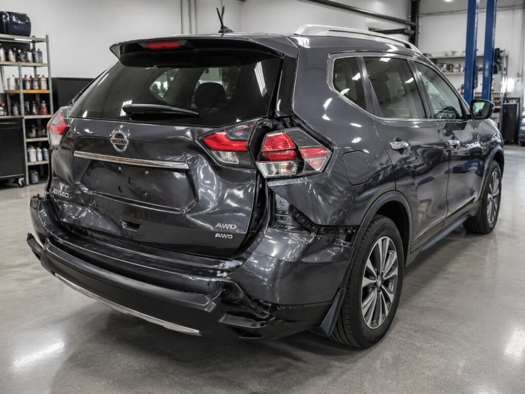 SUV with rear-end collision damage to bumper, tailgate, and rear panels in clean body shop bay.
